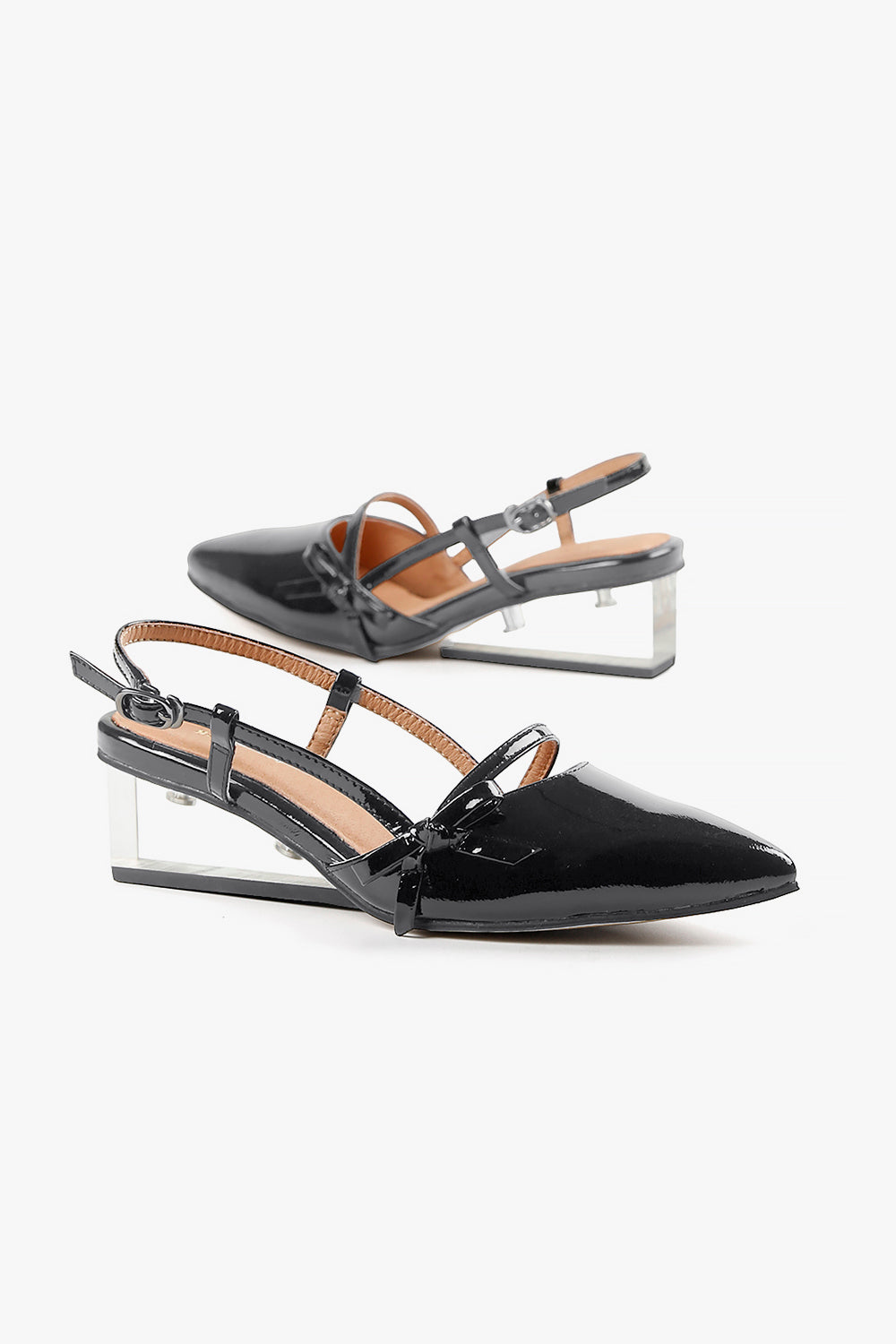 Women's glossy black pointed-toe heels with a sculptural see-through wedge and decorative bow accent.