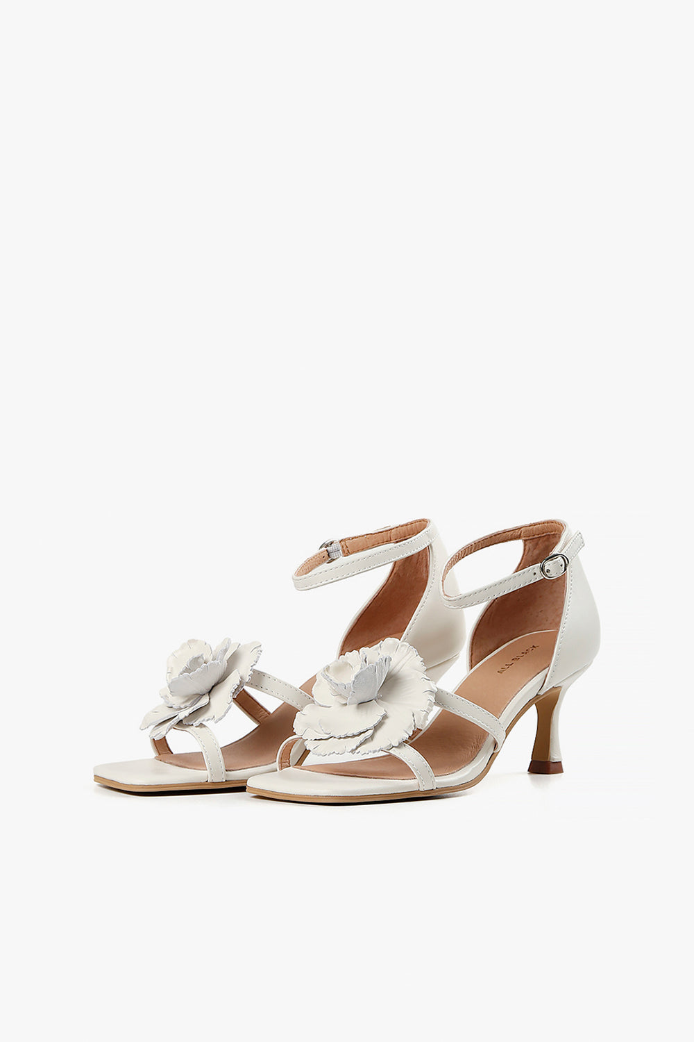 Pair of women's cream strappy sandals featuring an oversized handcrafted leather flower and slim kitten heel.