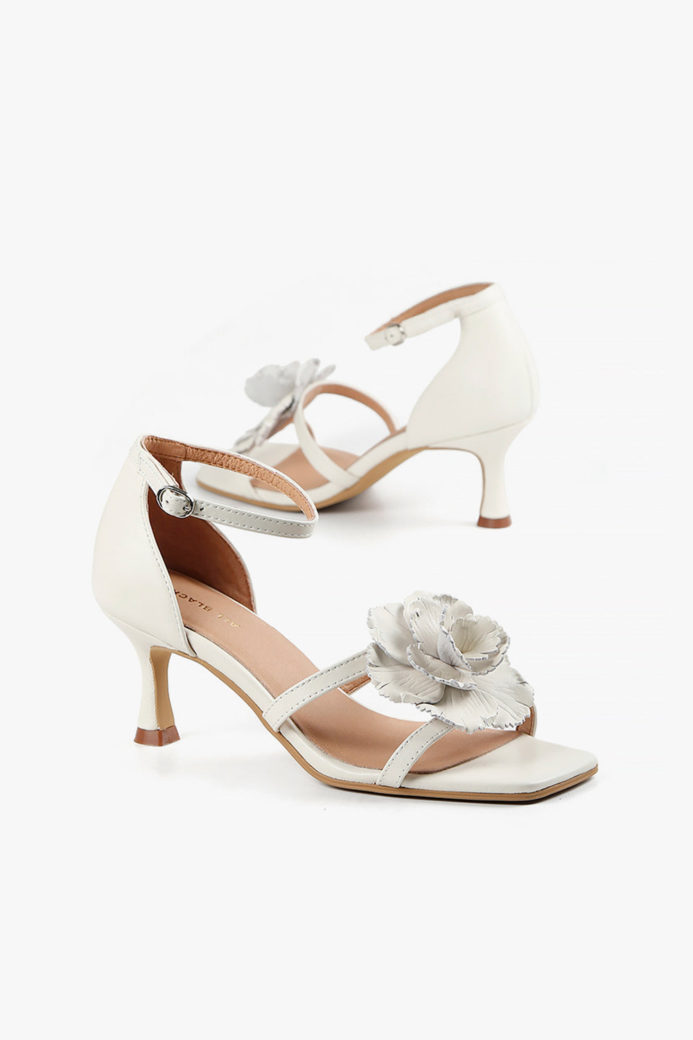 Back view of women's ivory kitten heels showcasing the closed heel counter and delicate ankle buckle strap.