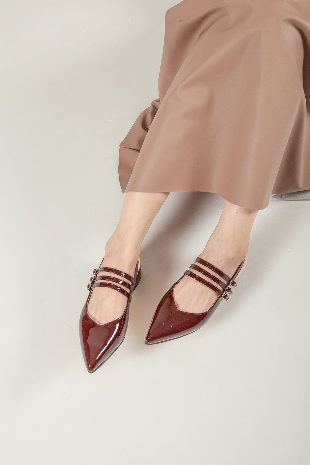 Women’s burgundy patent leather Mary Jane slingback pump worn with outfit, pointed toe and buckle straps, top view
