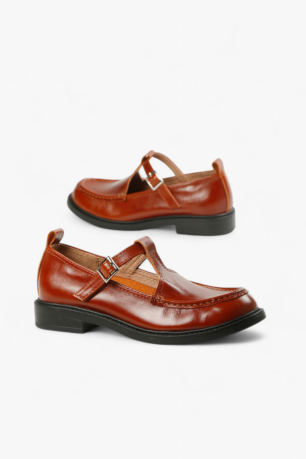 Pair of women's vintage-style cognac brown T-bar flats featuring decorative moc-toe stitching.