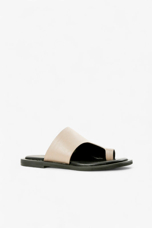 Women's taupe leather asymmetrical toe-loop slide sandals with black flat sole side view.