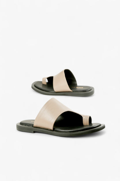 Pair of women's beige leather one-side sandals featuring a modern sculptural strap and toe loop.