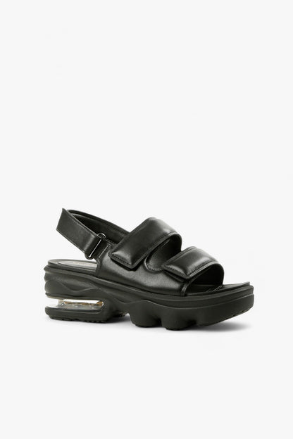 Women's black padded leather platform sandals with dual velcro straps and visible air cushion sole side view.