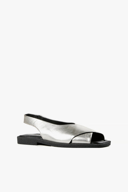 Women's silver metallic leather criss-cross sandals with backstrap and chunky black textured sole side view.