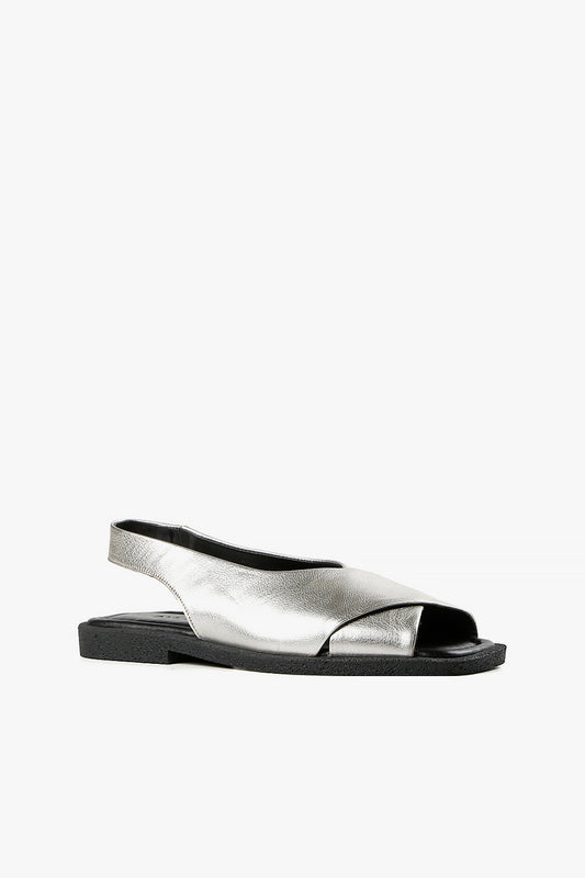 Women's silver metallic leather criss-cross sandals with backstrap and chunky black textured sole side view.