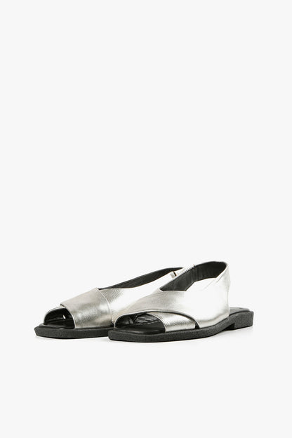Pair of women's metallic silver open-toe slingbacks featuring wide crossover straps and flat black outsoles.