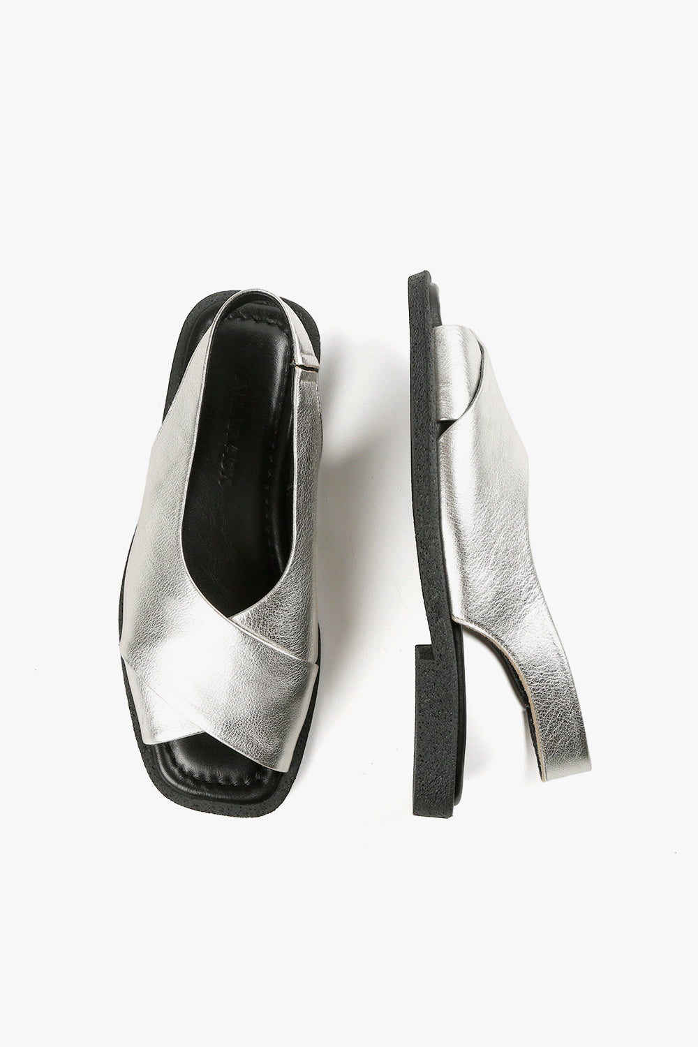 Top and side view of women's silver metallic crossover sandals showcasing square toe silhouette and textured black soles.